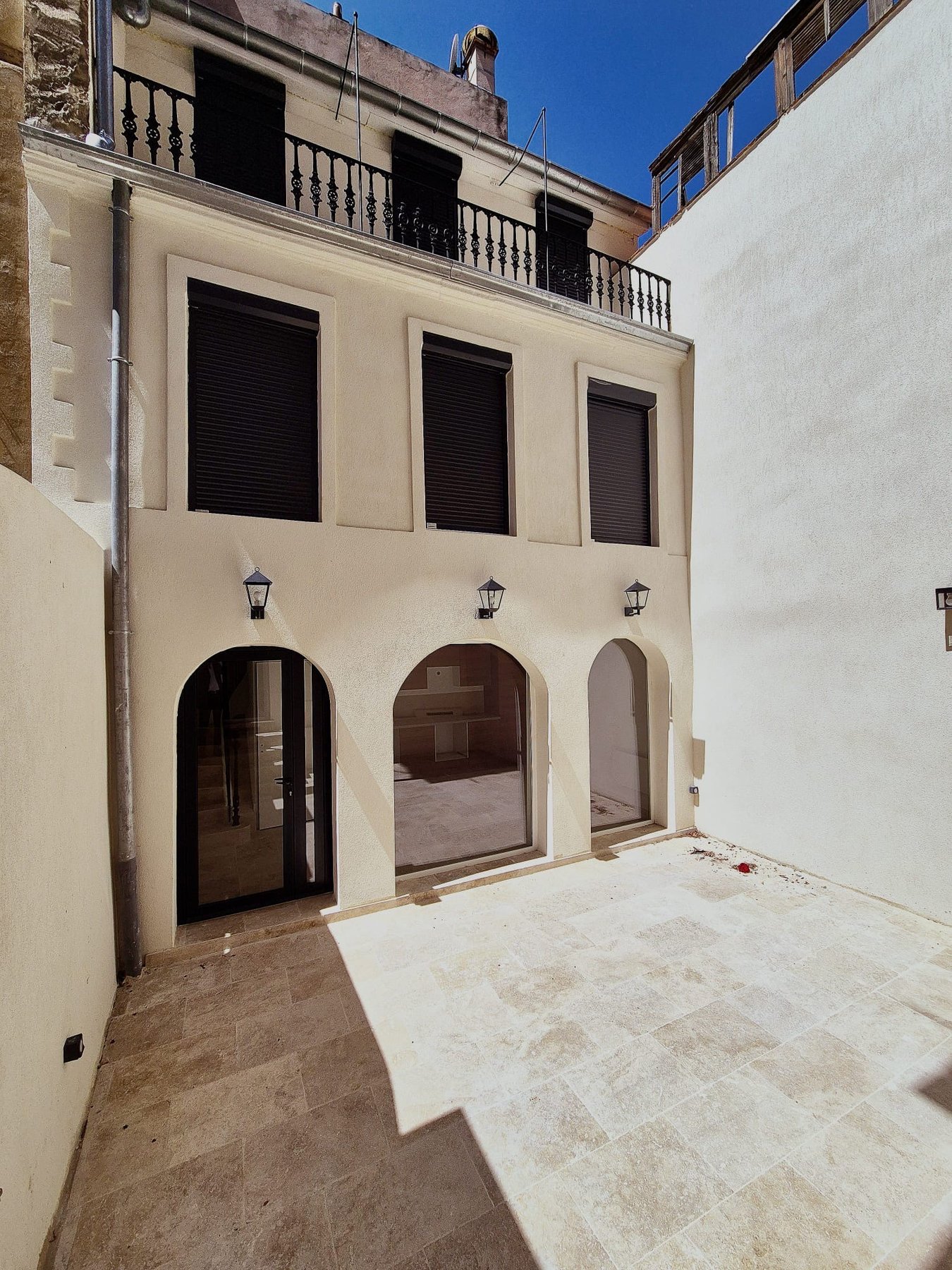 Cour intérieure rénovée à Marseille : façade ravalée, arches vitrées et sol en travertin