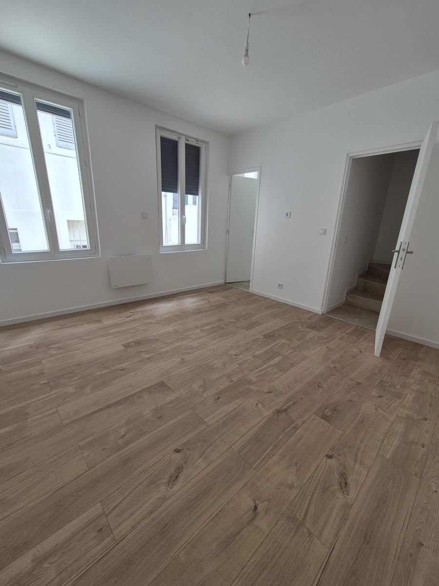 Pièce de vie avec parquet et accès à l'escalier